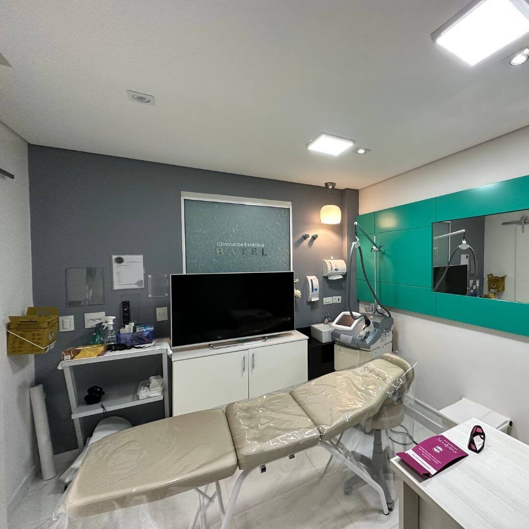 Sala de procedimentos com maca e parede verde